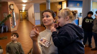 Eine Frau und ein Mädchen hängen Figur an einen Weihnachtsbaum.