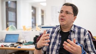 Mann spricht in Kamera und gestikuliert mit seinen Händen