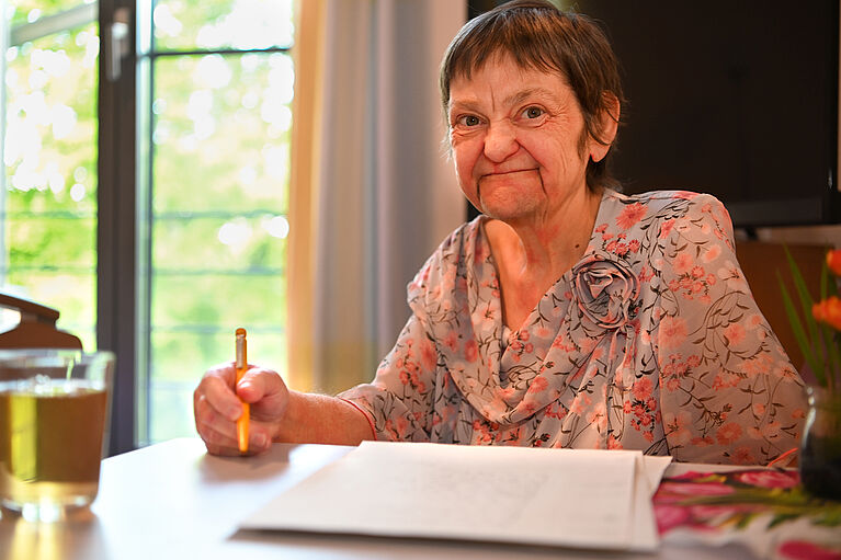 Frau aus Hospiz mit Stift und Papier