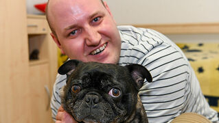 Arnoldas Lindsius cuddles with his dog.