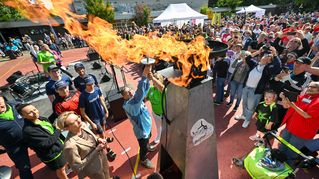 Das Olympische Feuer wird vor Publikum auf dem Sportplatz entzündet