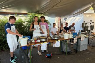 Jugendliche bereiten an einem Stand Crepes zu