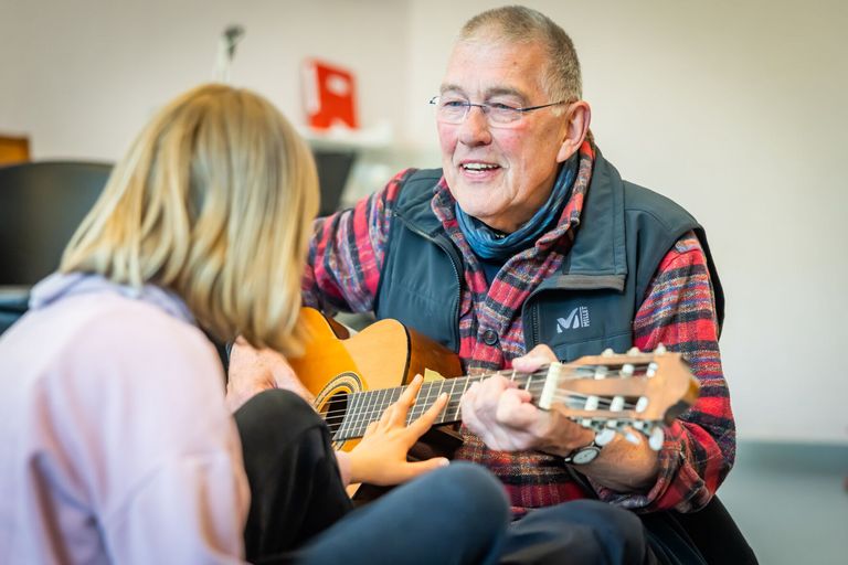 Wolfgang Spode spielt mit einer Schülerin Gitarre.