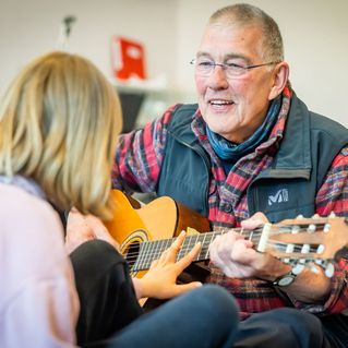 Wolfgang Spode spielt mit einer Schülerin Gitarre.