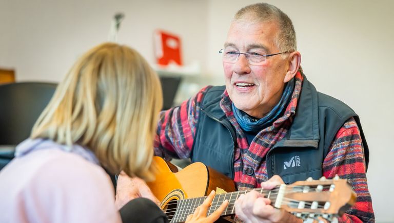 Wolfgang Spode spielt mit einer Schülerin Gitarre.