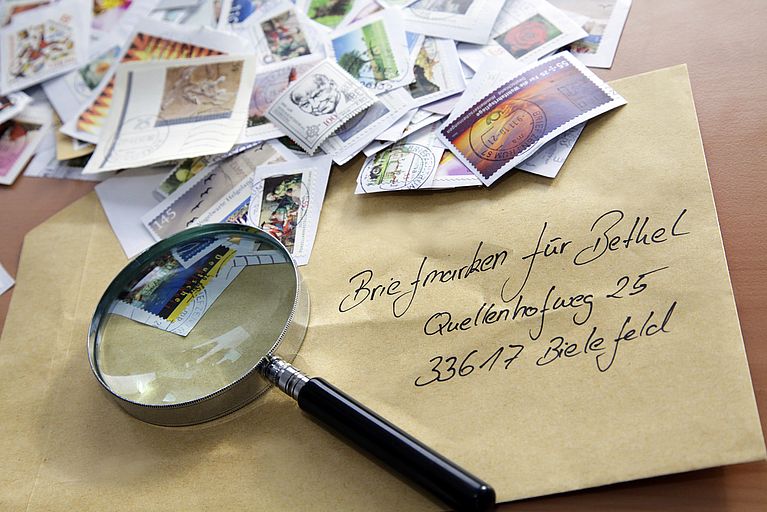 Stapel Briefmarken, Briefumschlag und Lupe