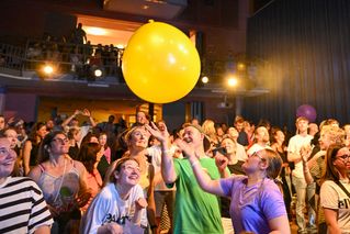 Ein gelber Luftballon fliegt übers Publikum