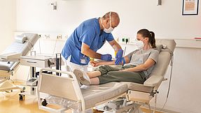 A nurse takes blood from a young woman.