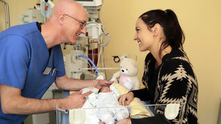 Staff and mother at the bedside of a baby