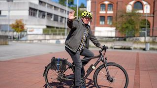 Mann sitzt auf dem Fahrrad und winkt.