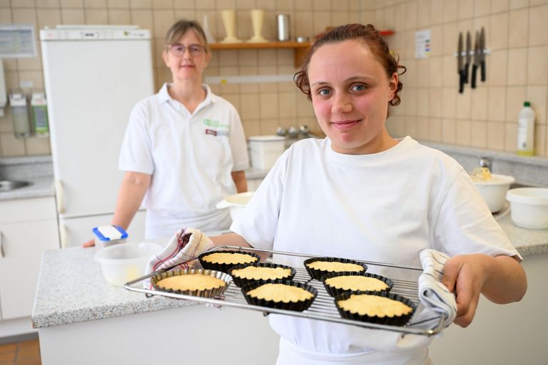 Eine junge Frau hält ein Backbleck mit Kuchen.