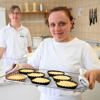 Eine junge Frau hält ein Backbleck mit Kuchen.