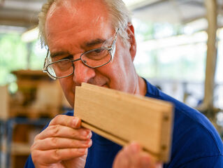 Employee checks wood cutting in the workshop.