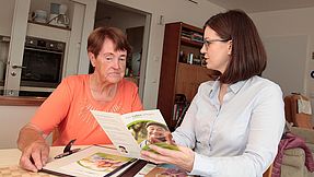 Woman shows flyer to senior citizen.