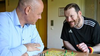 Pastor Dr. Bartolt Haase spielt eine Partie "Mensch ärgere dich nicht" mit Michael Schwarz.