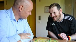 Pastor Dr. Bartolt Haase spielt eine Partie "Mensch ärgere dich nicht" mit Michael Schwarz.