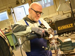 Ein Mann führt in einer Werkstatt Metallarbeiten durch.