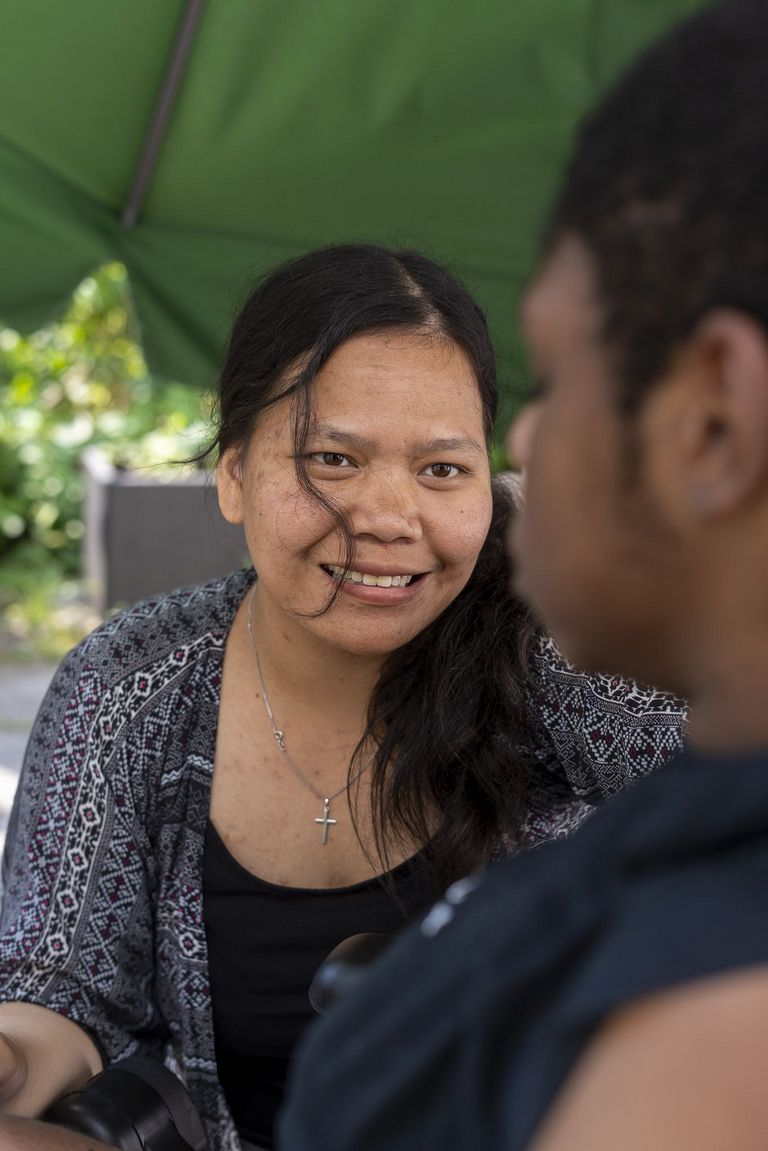 Debora Cici Rumahorbo reicht einem Klienten einen Becher an.