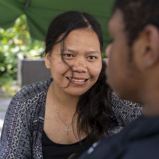 Debora Cici Rumahorbo reicht einem Klienten einen Becher an. 