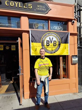Rainer Haarmann steht im Dortmund-Trikot vor einem Irish Pub.